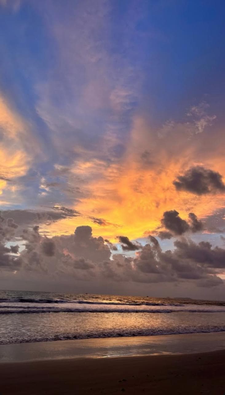 Sunset over the sea, orange cloud breaking across a blue sky